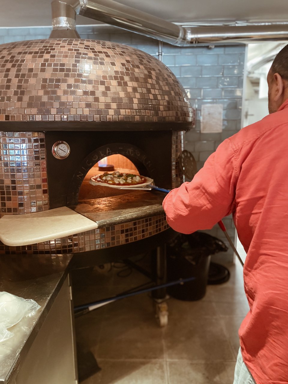 Ο Μάρκο Τζεναμπόνι βάζει την πίτσα μαργαρίτα για να ψηθεί στο φούρνο. 