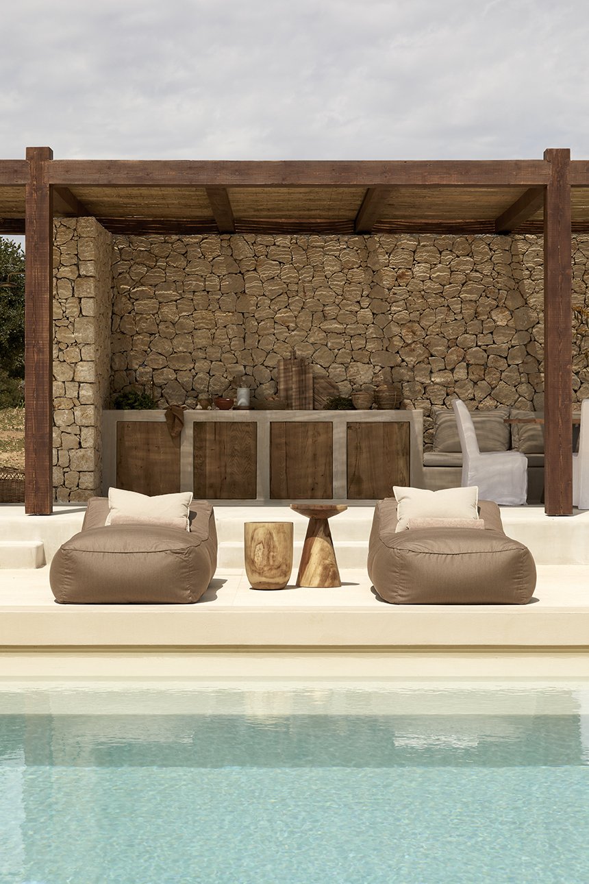 Η open-air κουζίνα με τον χτιστό πάγκο και τις ξύλινες πόρτες είναι τοποθετημένη μπροστά από τον πέτρινο τοίχο της κατοικίας - Φωτογραφία: Μυρτώ Ιατροπούλου / Courtesy of L Architects