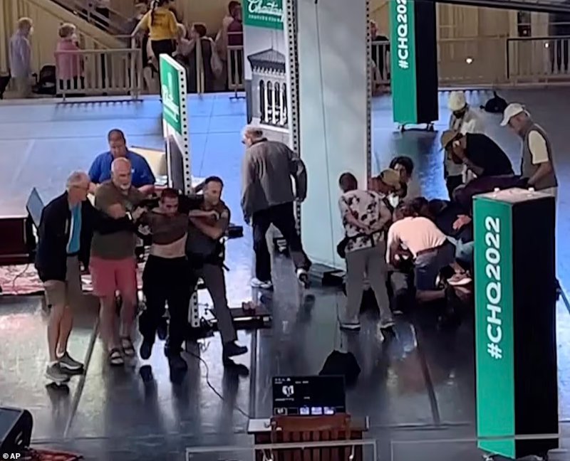 Παρευρισκόμενοι απομακρύνουν τον 24χρονο από το σημείο της επίθεσης στον Σαλμάν Ρούσντι