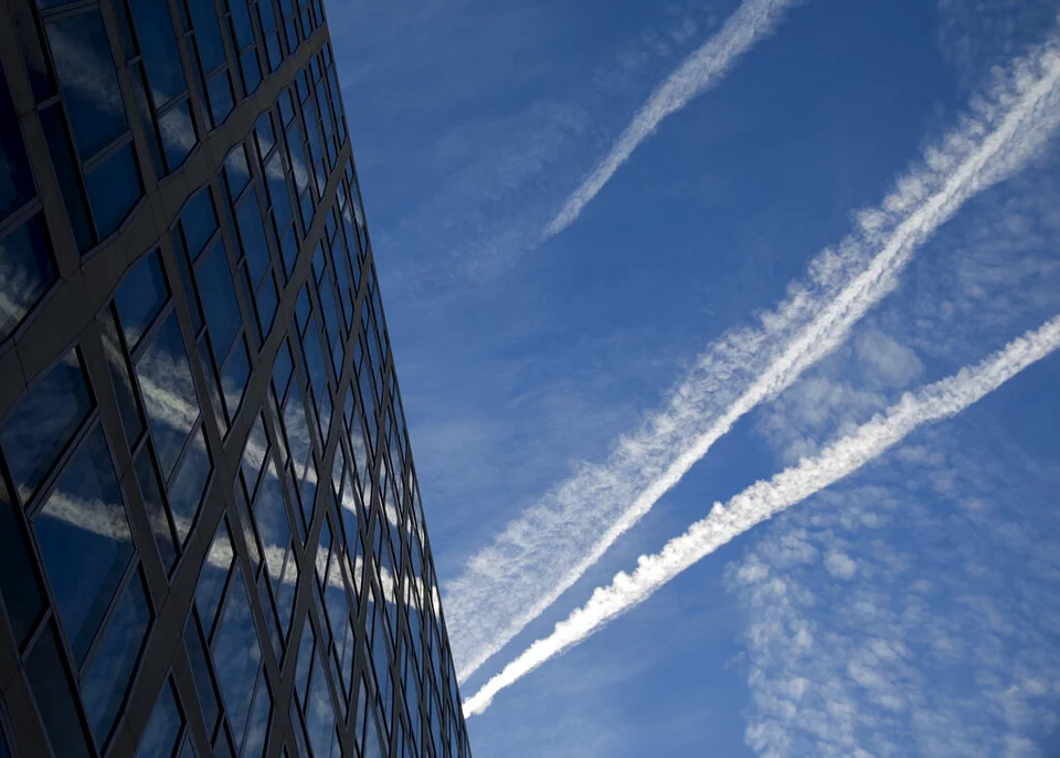 Τα ίχνη αεροπλάνου αντανακλώνται σε ένα κτίριο καθώς διασχίζουν τον πρωινό ουρανό πάνω από τη Λεωφόρο Πενσυλβάνια στην Ουάσινγκτον 