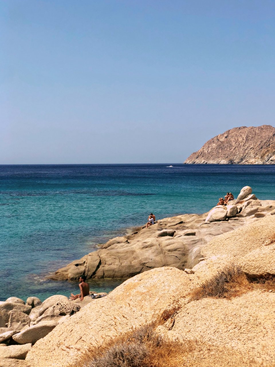 Κολύμπι και ηλιοθεραεία στα βράχια με φόντο το απέραντο γαλάζιο - Φωτογραφία: Despina Galani/Unsplash