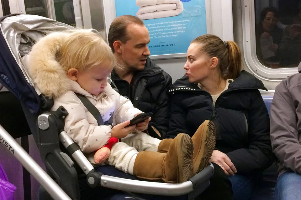 Ένα κοριτσάκι παίζει με ένα κινητό τηλέφωνο ενώ ταξιδεύει σε μετρό της Νέας Υόρκης