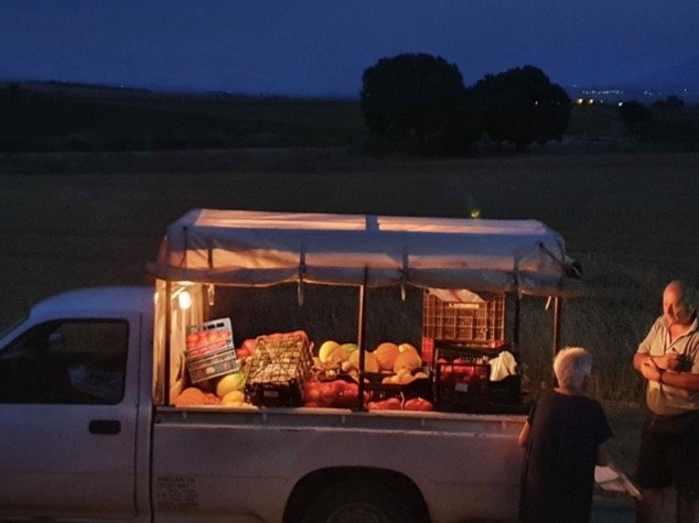 Στο site του εστιατορίου Ola Kala ο Αντώνης Δέτσης θέλοντας να υπογραμμίσει το ελληνικό στοιχείο της κουζίνας του έχει επιλέξει αυτή τη φωτογραφία: ένα υπαίθριο μανάβικο σε αγροτικό αυτοκίνητο, μια οικεία εικόνα των αθηναϊκών προαστίων τη δεκαετία του '80 και της ελληνικής επαρχίας.&nbsp;