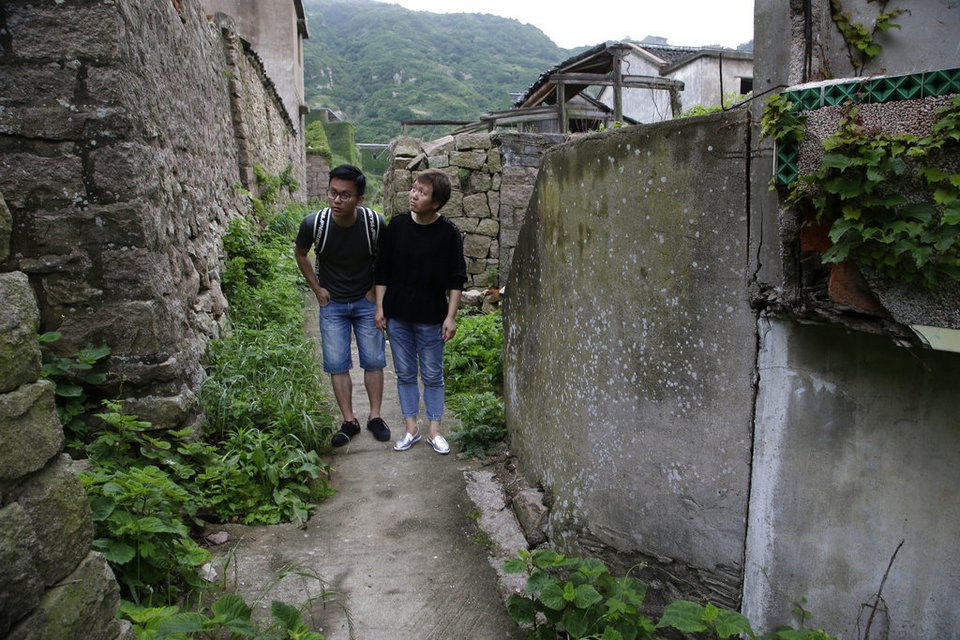 Η Zhu Mandi, 50 ετών, δεξιά, και ο γιος της, Wang Yi, 27 ετών, περπατούν προσεκτικά μέσα στο πρώην ψαροχώρι Houtouwan για να βρουν το σπίτι που εγκατέλειψε η οικογένειά τους το 1995