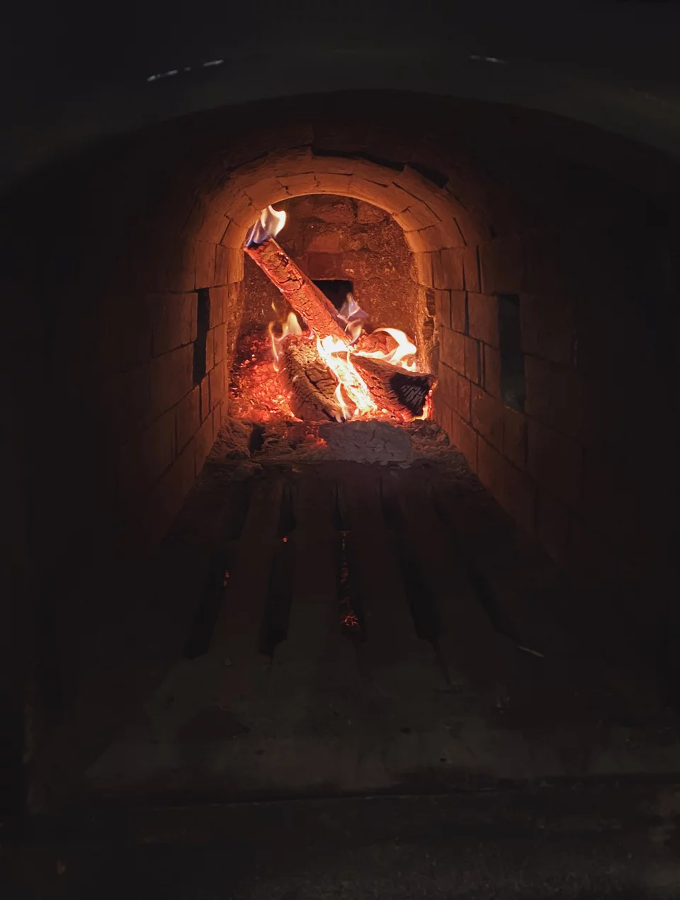 Η φωτιά στη βάση του ξυλόφουρνου, κάτω από την εστία με πυρότουβλα, καίει συνέχεια, όλη μέρα.