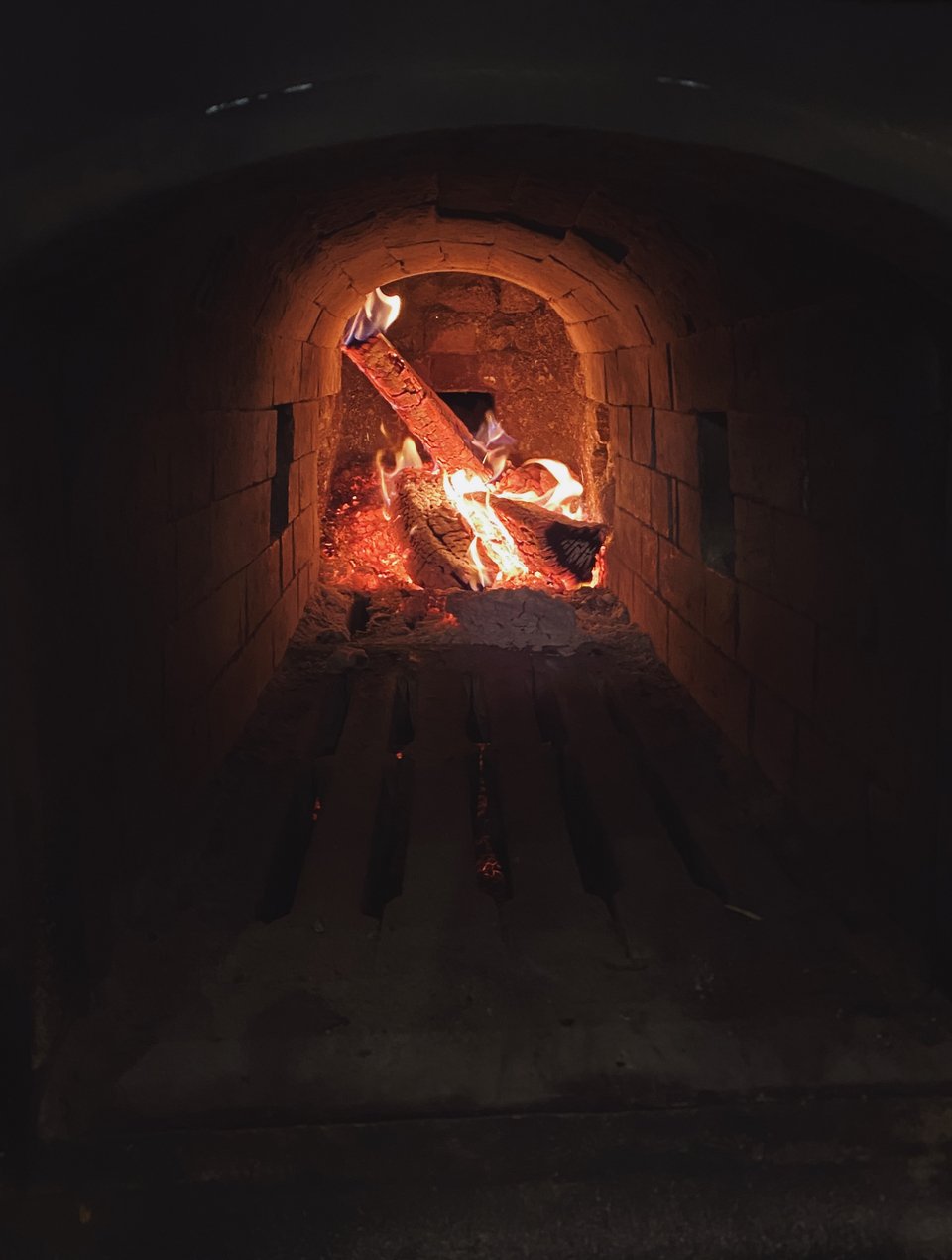Η φωτιά στη βάση του ξυλόφουρνου, κάτω από την εστία με πυρότουβλα, καίει συνέχεια, όλη μέρα. 