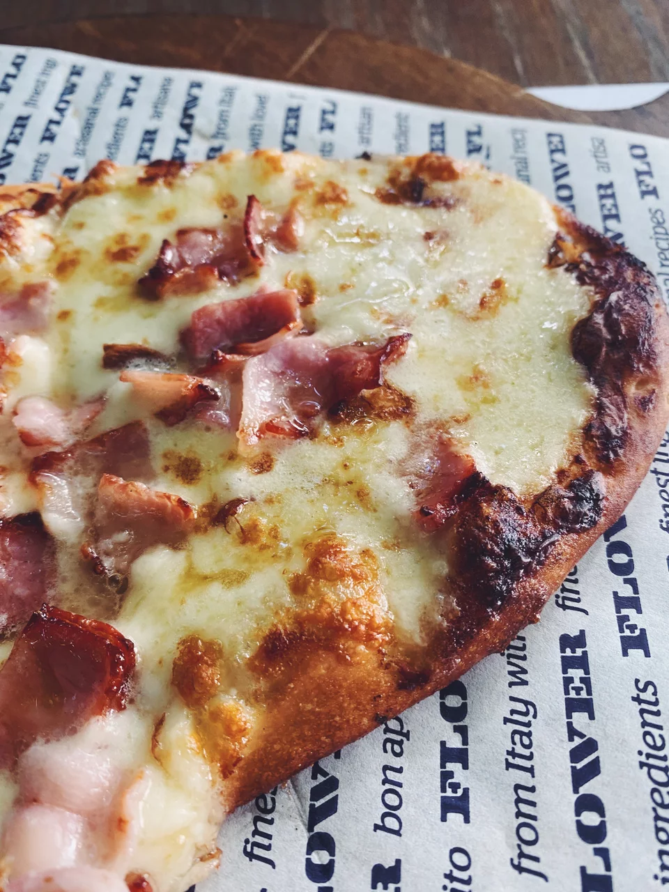 Η λευκή πίτσα Bacon & Maple Syrup με κρέμα παρμεζάνας, μοτσαρέλα, μπέικον, καραμελωμένο κρεμμύδι, φρέσκο πιπέρι και σιρόπι σφενδάμου, σε ατομικό μέγεθος.