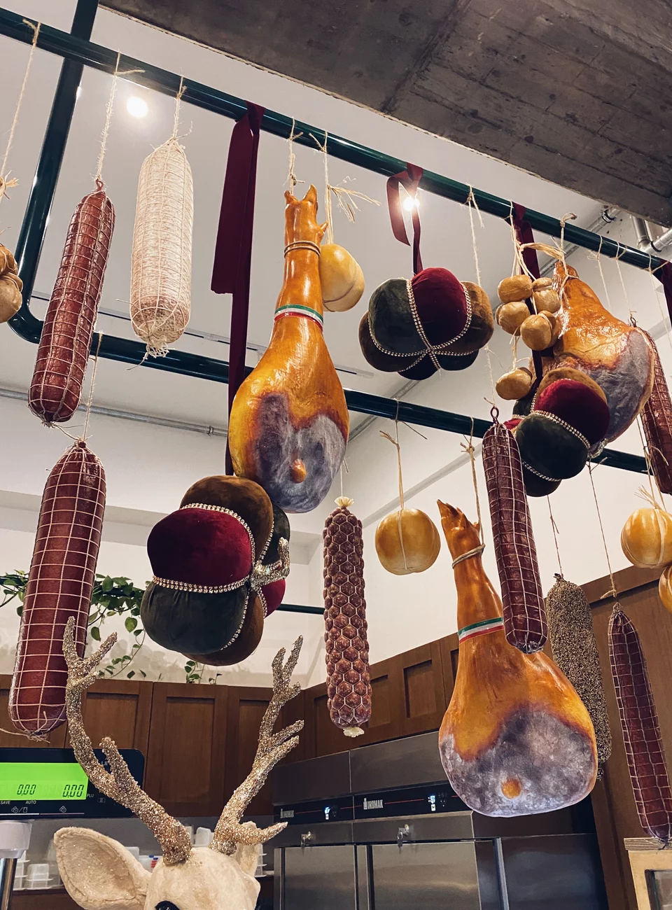 Αλλαντικά κρεμασμένα από ράγες πάνω από το ψυγείο με τα τυριά -μια τυπική εικόνα ιταλικού μπακάλικου.