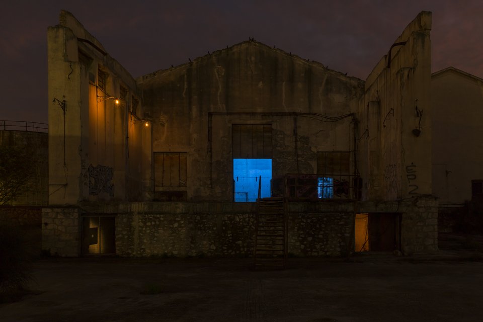 Oψη του εργοστασίου καθώς πλησιάζεις μέσα στη νύχτα. Το μπλε χρώμα, μέρος της εγκατάστασης του Δημήτρη Καμαρωτού