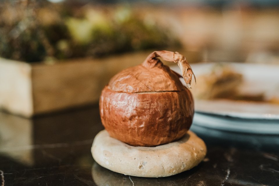 Το ψητό κρεμμύδι λειτουργεί σαν σκεύος σερβιρίσματος αλλά προσφέρει και πλούσια αρώματα στο τελικό αποτέλεσμα. Είναι γεμισμένο με σιταρότο (μελωμένο σιτάρι) / Φωτογραφία: Παναγιώτης Μάλλιαρης/iefimerida