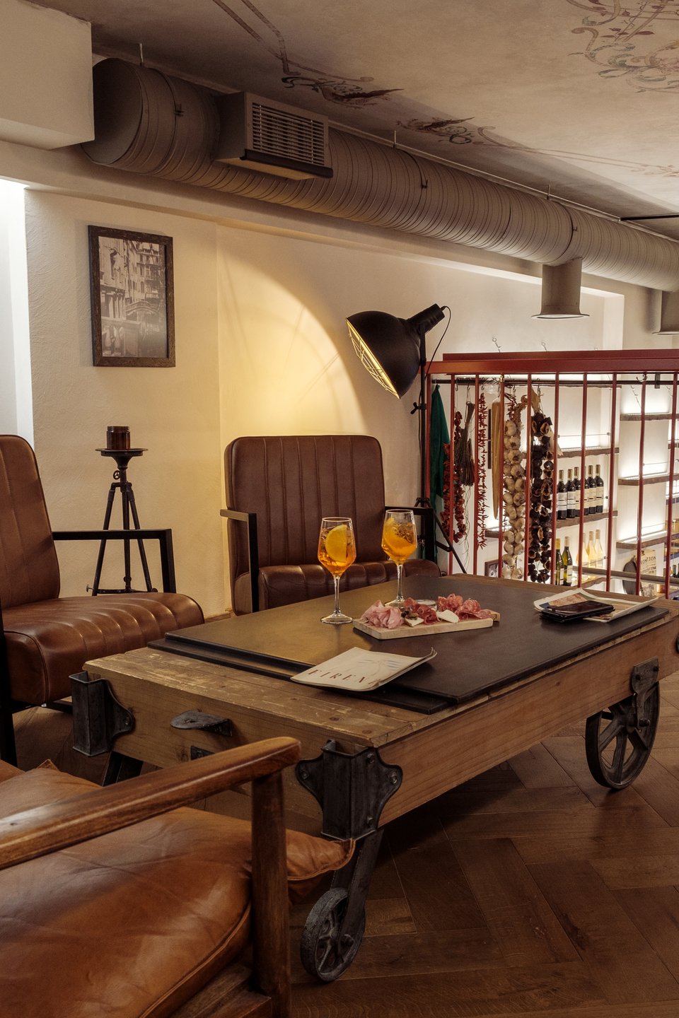 Στο πατάρι με τη ζωγραφισμένη στο χέρι οροφή και τις δερμάτινες πολυθρόνες μπορεί κανείς να απολαύσει το κρασί ή το aperitivo του, σε έναν χώρο με έντονη τοσκανέζικη προσωπικότητα
