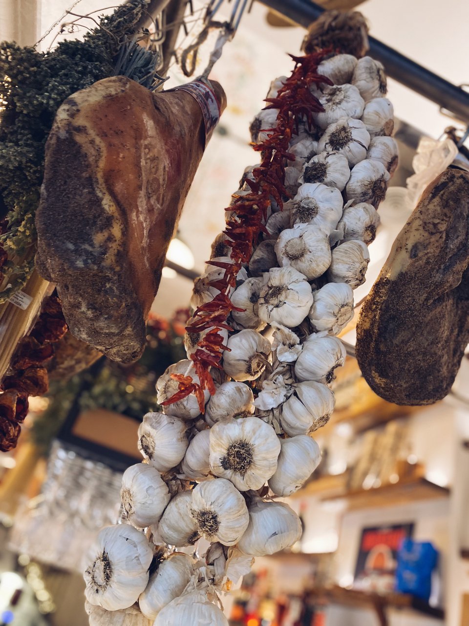 Πλεξούδες με ιταλικά σκόρδα από την Τοσκάνη, γιρλάντες από λιαστή ντομάτα και παλαιωμένα αλλαντικά και μυρωδικά κρέμονται στο μπαρ