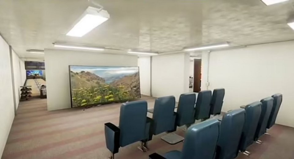 Μια κινηματογραφική αίθουσα σε ένα πολυτελές καταφύγιο επιβίωσης Rising S. Στο βάθος, διακρίνεται μια αίθουσα μπόουλινγκ.  