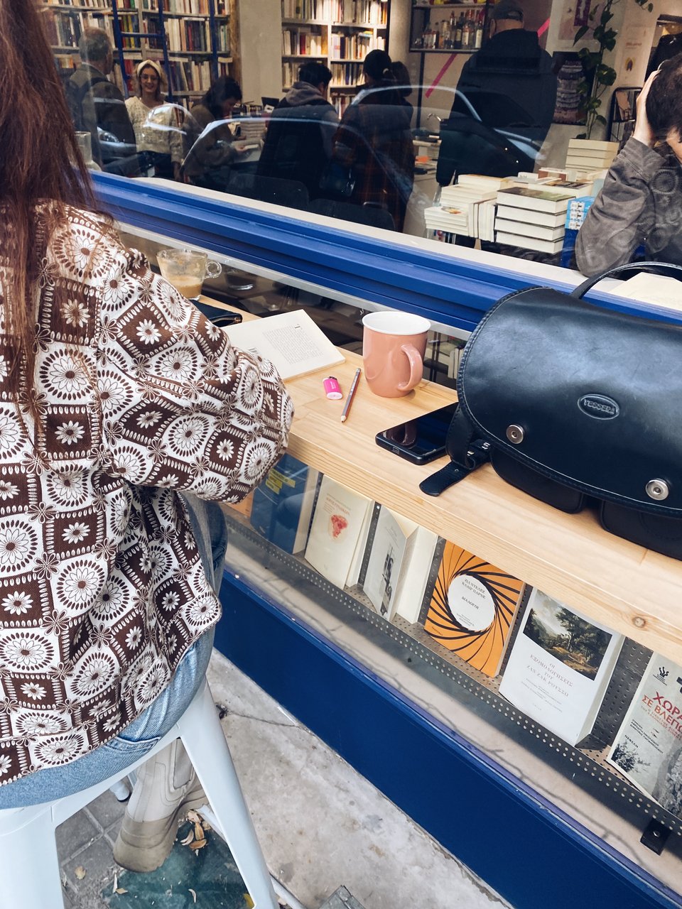 Στον πάγκο, στην τζαμαρία του «Κομπραί», οι επισκέπτες απολαμβάνουν τον καφέ και το βιβλίο τους / Φωτογραφία: Μάνος Λειβαδάρος/iefimerida