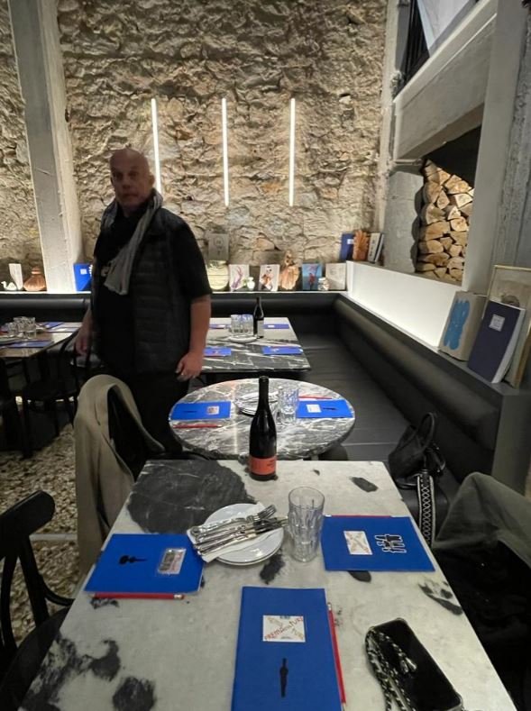 Ο Δημήτρης Αντωνίτσης. Στα τραπέζια τα τετράδια από τις εκθέσεις του Hydra School Project