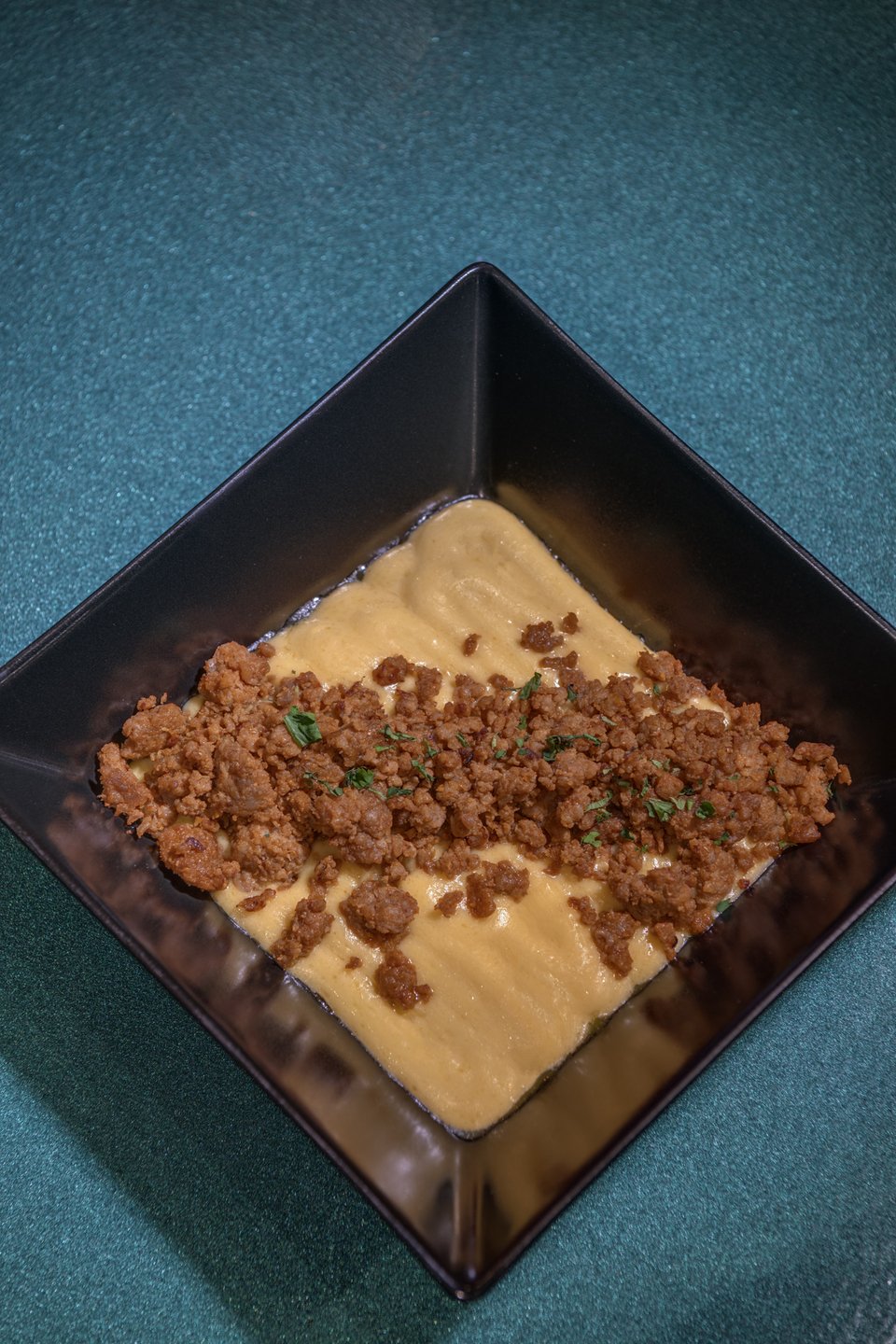 Η κρέμα τυριού που συνοδεύει τα νάτσος στο ορεκτικό Choriqueso, έχει φρέσκο chorizo και κόλιαντρο.