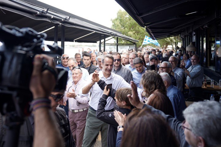 Ο Κυριάκος Μητσοτάκης χαιρετά κόσμο καθώς περνά από καφετέρια