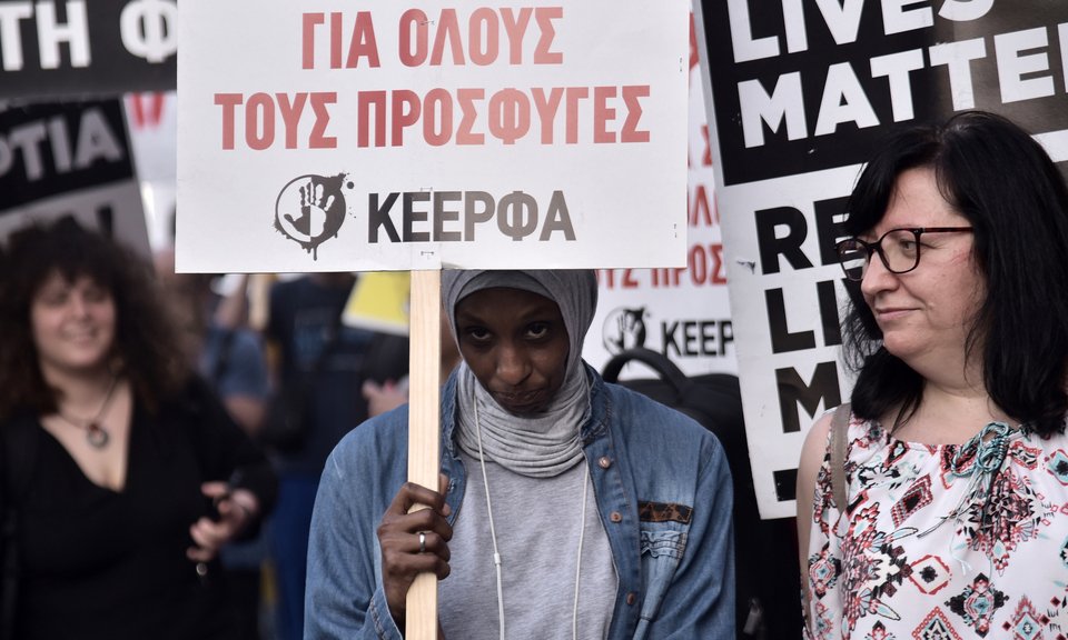 Μουσουλμάνα διαδηλώτρια με πλακάτ για τους πρόσφυγες