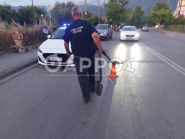 Αστυνομικός μεταφέρει το πατίνι από το δρόμο που έγινε η σύγκρουση / Φωτογραφία tharrosnews.gr