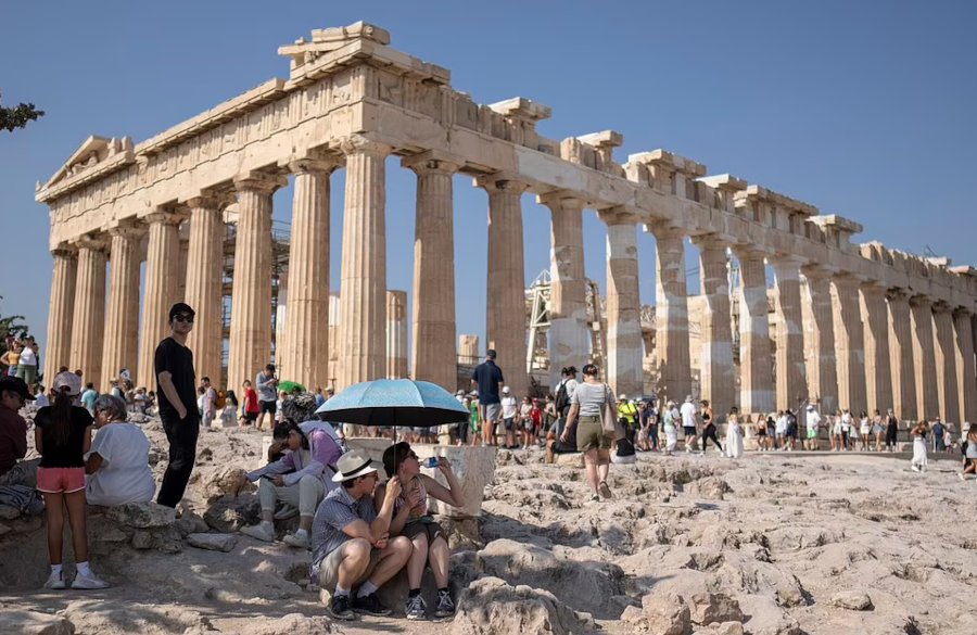 Τουρίστες προσπαθούν να προστατευθούν από τον καυτό ήλιο στην Ακρόπολη