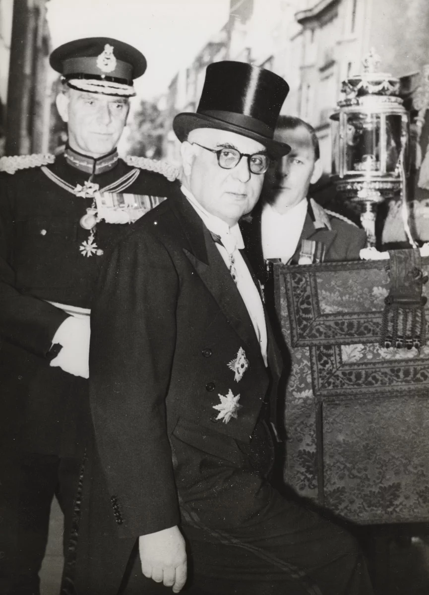 Λονδίνο, 6 Ιουνίου 1957. Ο Γιώργος Σεφέρης μεταβαίνει από την πρεσβευτική κατοικία στο παλάτι του Μπάκιγχαμ με την παραδοσιακή άμαξα, όπου θα επιδώσει τα διαπιστευτήριά του στη βασίλισσα Ελισάβετ. Η φωτογραφία αυτή διανεμήθηκε από το Γαλλικό Πρακτορείο Ειδήσεων την ημέρα της αναγγελίας του Νόμπελ Λογοτεχνίας στον Σεφέρη.