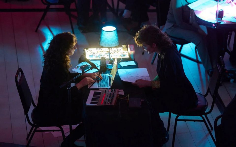 Η Nάντα Ελ Νάζλι και η Σίστερ Σταλόνε καθισμένες στην κονσόλα. Δυο φορές σηκώνεται η κάθε μία και κινείται στο κοινό, μιλώντας ή τραγουδώντας