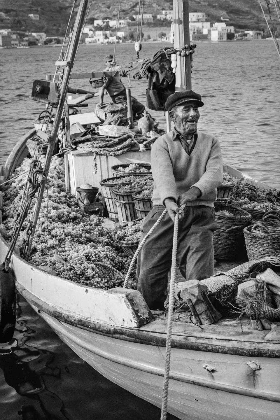 Κατάπολα, Αμοργός, 1960. Καΐκι με φορτίο από σταφύλια φτάνει στο λιμάνι το σούρουπο. Λόγω της απουσίας καλών οδικών δικτύων στα νησιά εκείνη την περίοδο, τα καΐκια χρησιμοποιούνταν συχνά και για ενδονησιωτικές μεταφορές.