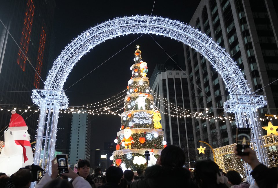 Άνθρωποι συγκεντρώνονται γύρω από ένα χριστουγεννιάτικο δέντρο στο ρέμα Cheonggye την παραμονή των Χριστουγέννων στη Σεούλ της Νότιας Κορέας / AP Photo/Ahn Young-joon