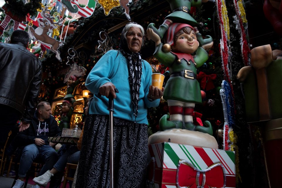 Μια ηλικιωμένη γυναίκα περπατάει στην περιοχή του Ψυρρή στην Αθήνα την παραμονή των Χριστουγέννων, Κυριακή 24 Δεκεμβρίου 2023 / AP Photo/Michael Varaklas