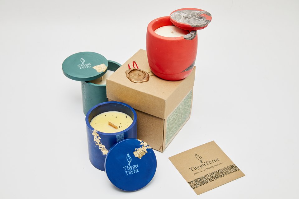 Κηροπήγια Τhygga Terra (από τη ελληνική «θυγατέρα» και τη λατινική “terra”, που σημαίνει «γη»).  Σχέδια εμπνευσμένα από χειροποίητους θησαυρούς που μας κληροδότησαν γιαγιάδες και μαμάδες. Τα κεριά είναι από οικολογικά, βιώσιμα υλικά.