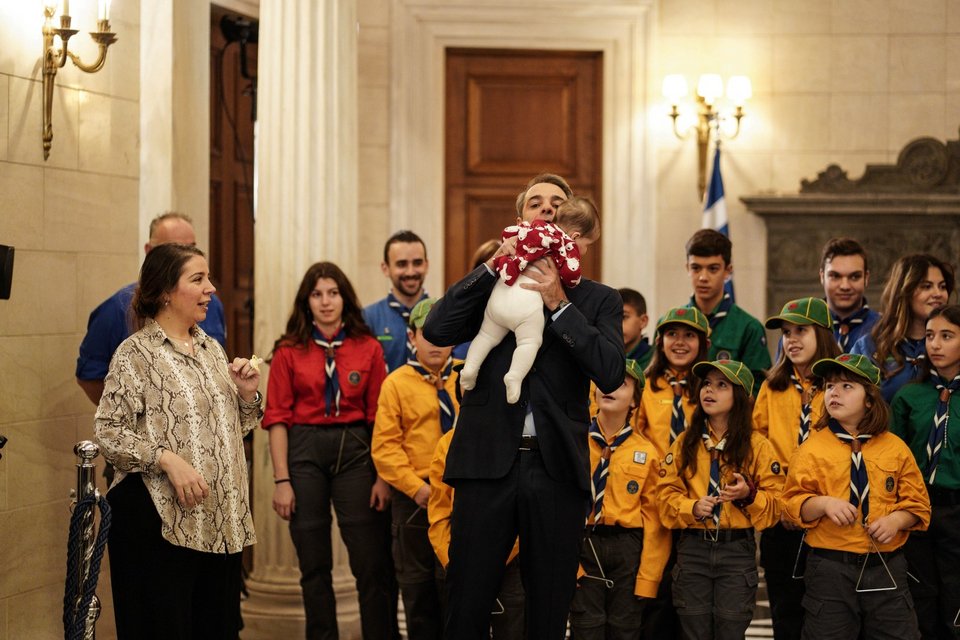 Ο Κυριάκος Μητσοτάκης παίρνει αγκαλιά ένα μωρό ακούγοντας τα κάλαντα στο Μαξίμου -Φωτογραφία: Nick Paleologos / SOOC