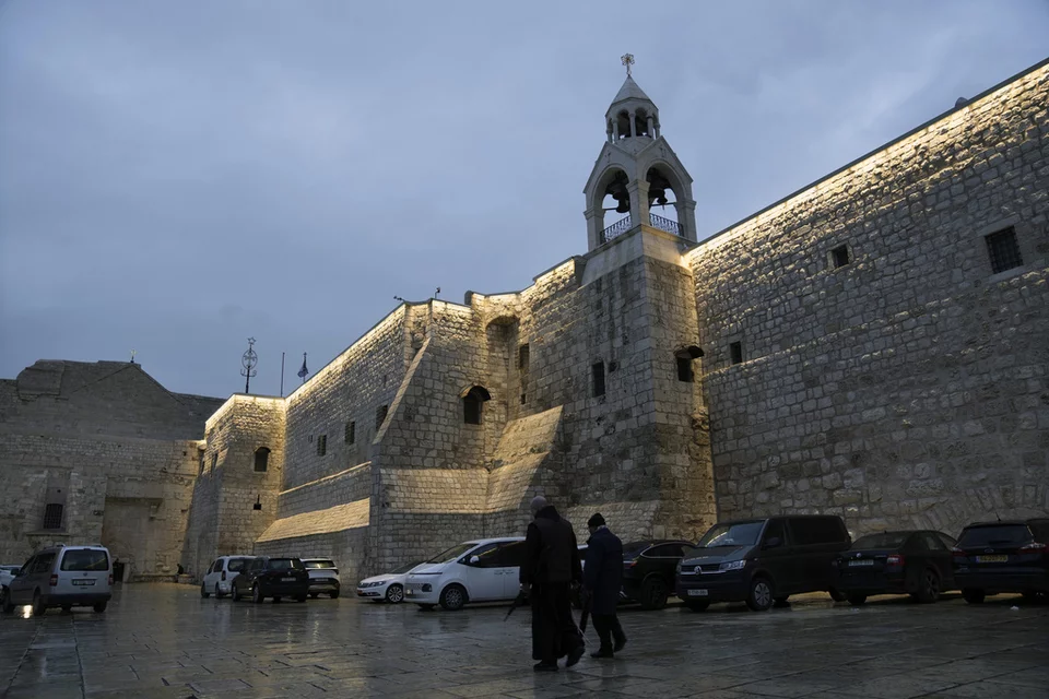 Άνθρωποι περπατούν δίπλα από την εκκλησία της Γέννησης, στην πόλη Βηθλεέμ της Δυτικής Όχθης, Παρασκευή, 23 Δεκεμβρίου 2023 / Φωτογραφία: AP Photo/Mahmoud Illean