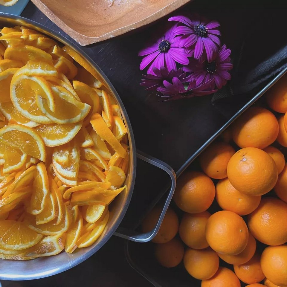 Τα πορτοκάλια στην κουζίνα κόβονται και μπαίνουν στην κατσαρόλα για να βράσουν.