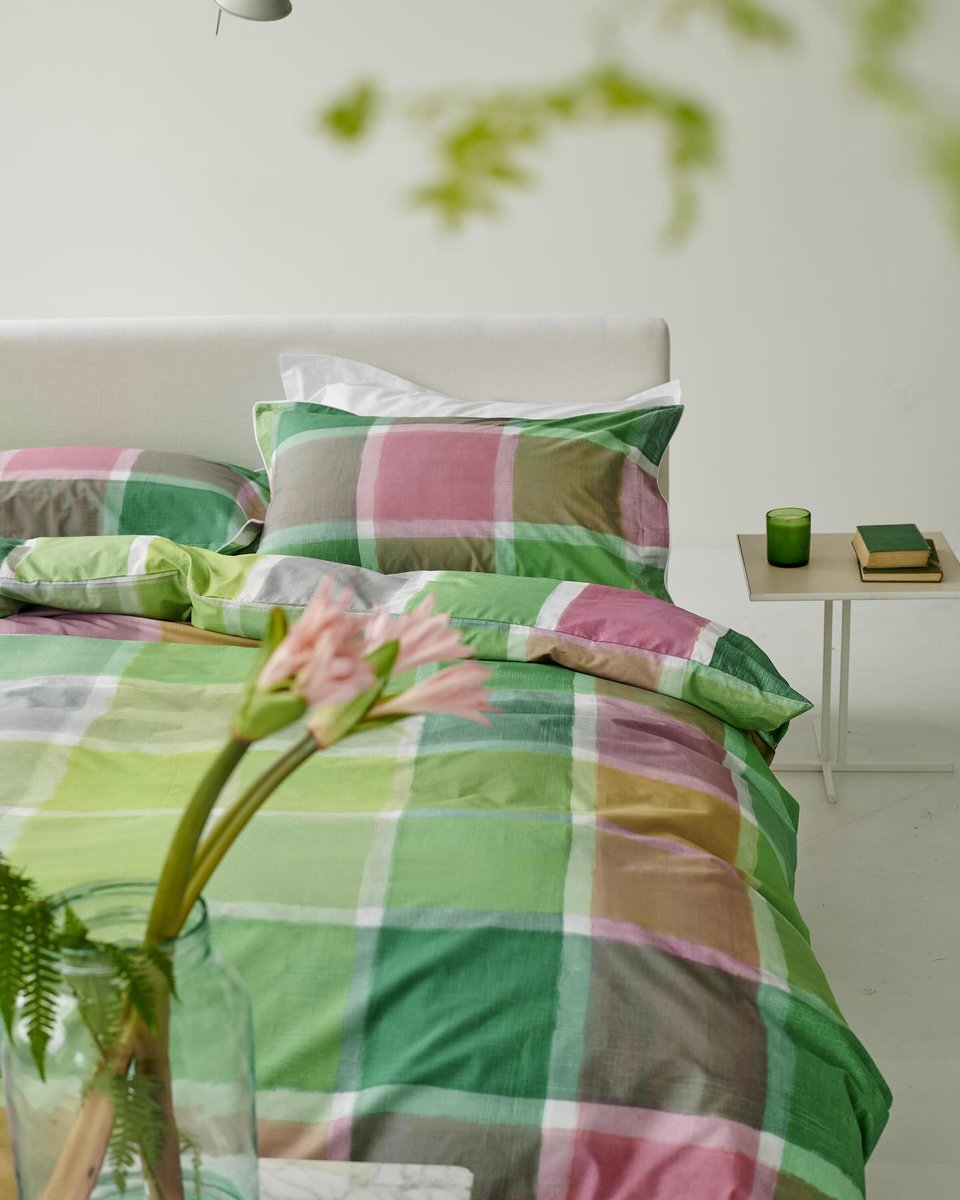 Λευκά είδη του οίκου Designers Guild σε πολύχρωμα καρό, μπροστά από έναν ολόλευκο τοίχο / Φωτογραφία:  Courtesy of Designers Guild / @designersguild/Instagram