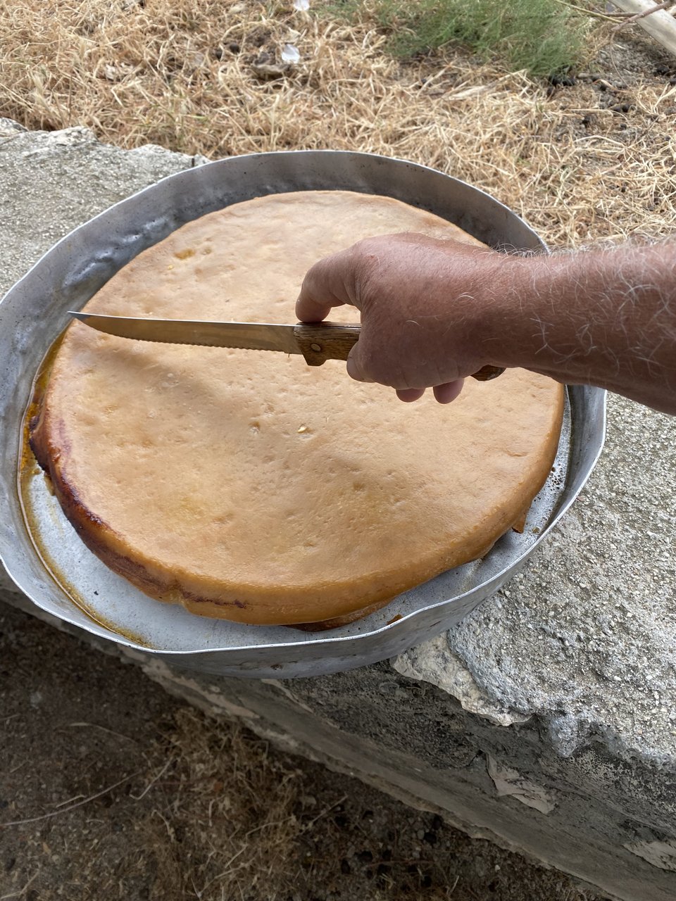 Η κρεατόπιτα κόβεται με το μαχαίρι από τον Γιώργο Γράνα στην παραλία Σωτήρας στη Θηνιά.