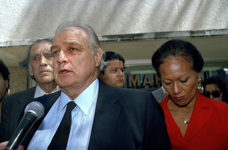 Ο ηθοποιός Μάρλον Μπράντο και η σύζυγός του, Ταρίτα Τεριιπάια, αποχωρούν από ακρόαση για την εγγύηση του γιου του Μπράντο, Κρίστιαν Μπράντο, ο οποίος συνελήφθη μετά τον θανάσιμο πυροβολισμό του Νταγκ Ντρολέ, φίλου της Σάγιεν Μπράντο