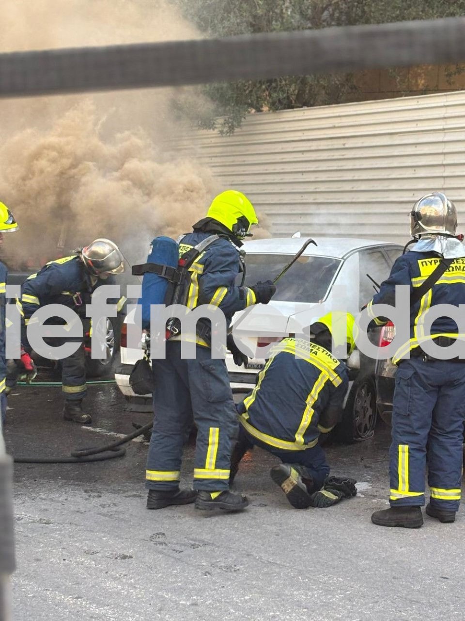 Καπνοί έβγαιναν από το αυτοκίνητο, ενώ πυροσβέστες επιχειρούσαν για να σβήσουν τη φωτιά