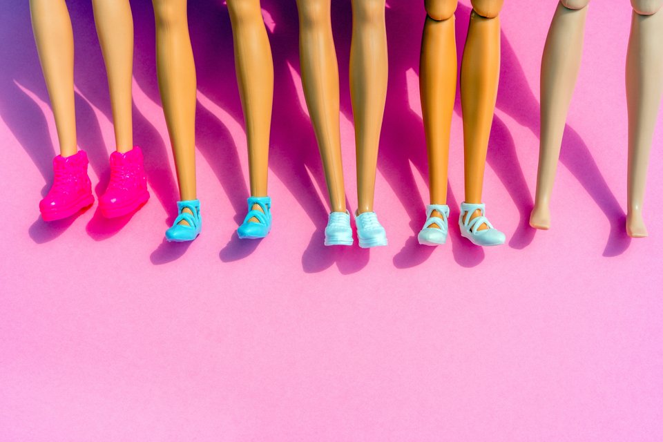 Πόδια κουκλών Barbie με παπούτσια και χωρίς σε ροζ φόντο