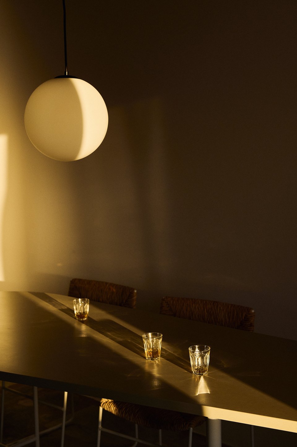 Ένα φωτιστικό σε σχήμα σφαίρας έχει τοποθετηθεί πάνω από το λιτό μοντέρνο τραπέζι / Φωτογραφία: Valiana Variantza - @blenderfactory
