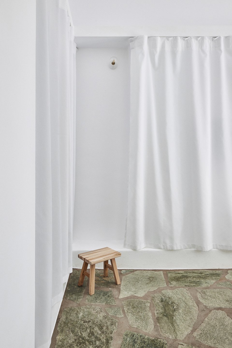 Ένα ξύλινο σκαμπό, μοναδικό στολίδι σε αυτή τη λιτή γωνιά / Φωτογραφία: Valiana Variantza - @blenderfactory