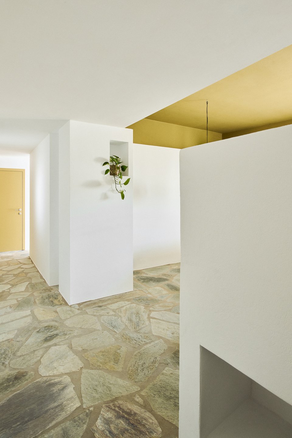 Οι γήινες αποχρώσεις της πέτρας συνυπάρχουν αρμονικά με τον κεχριμπαρένιο τόνο με τον οποίο έχει βαφτεί η οροφή / Φωτογραφία: Valiana Variantza - @blenderfactory