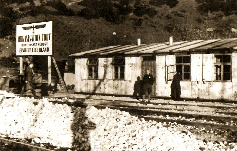 Κτήριο Διοίκησης Τοντ δίπλα στο πέτρινο κτήριο των κλειδούχων. Πινακίδα της Todt στον Σταθμό της Καρυάς