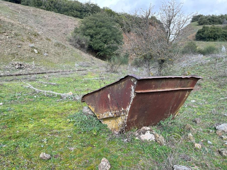 Στον χώρο πίσω από το βουνό που έγινε η τομή βρίσκονται ακόμα σημάδια από τα έργα, ράγες, καρότσι βαγονέτου