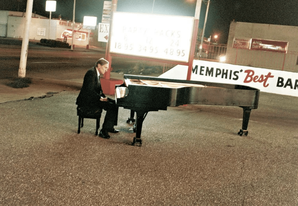 Στο Μέμφις, εκεί όπου ο William Eggleston περπάτησε για πρώτη φορά με βλέμμα γεμάτο χρώμα, τραβήχτηκε αυτή η φωτογραφία. Κάποτε ταξίδεψαν στη Βαυαρία για να φωτογραφίσουν μαζί και δεν τράβηξαν ούτε ένα καρέ. «Η φωτογραφία», είπε ο Eggleston, «είναι απλώς μια αφορμή για να βγαίνουμε από το σπίτι».