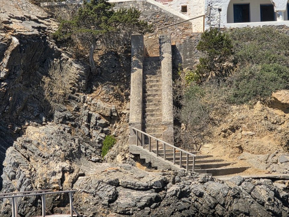 Μια στενή τσιμεντένια σκάλα οδηγεί στη θάλασσα όπου υπάρχει μια μικρή προβλήτα