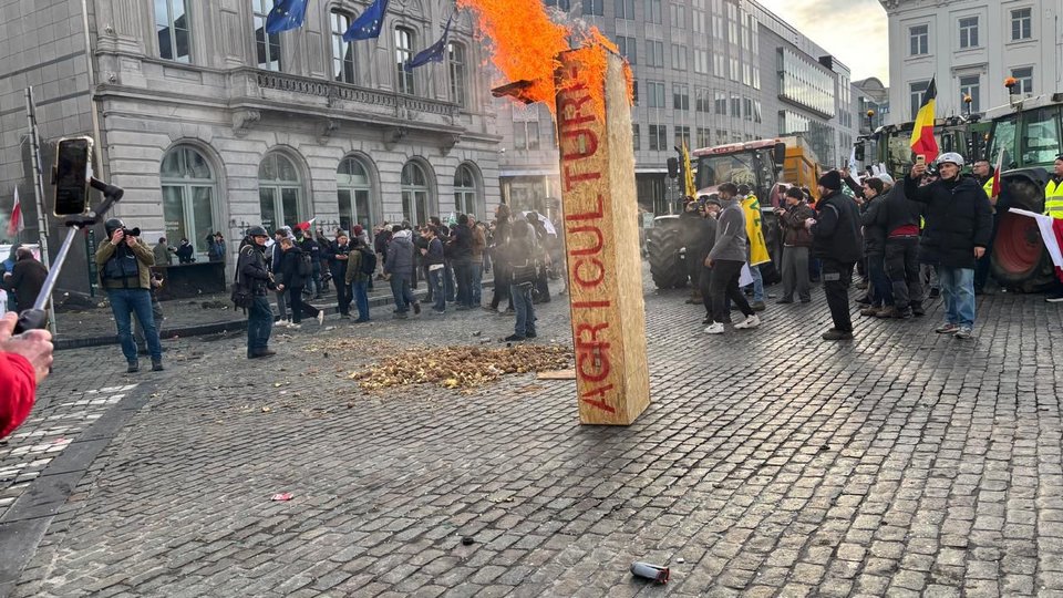 Διαδηλωτές-αγρότες καίνε συμβολικά στις Βρυξέλλες ξύλινο μπλοκ που γράφει πάνω «αγροτική παραγωγή»