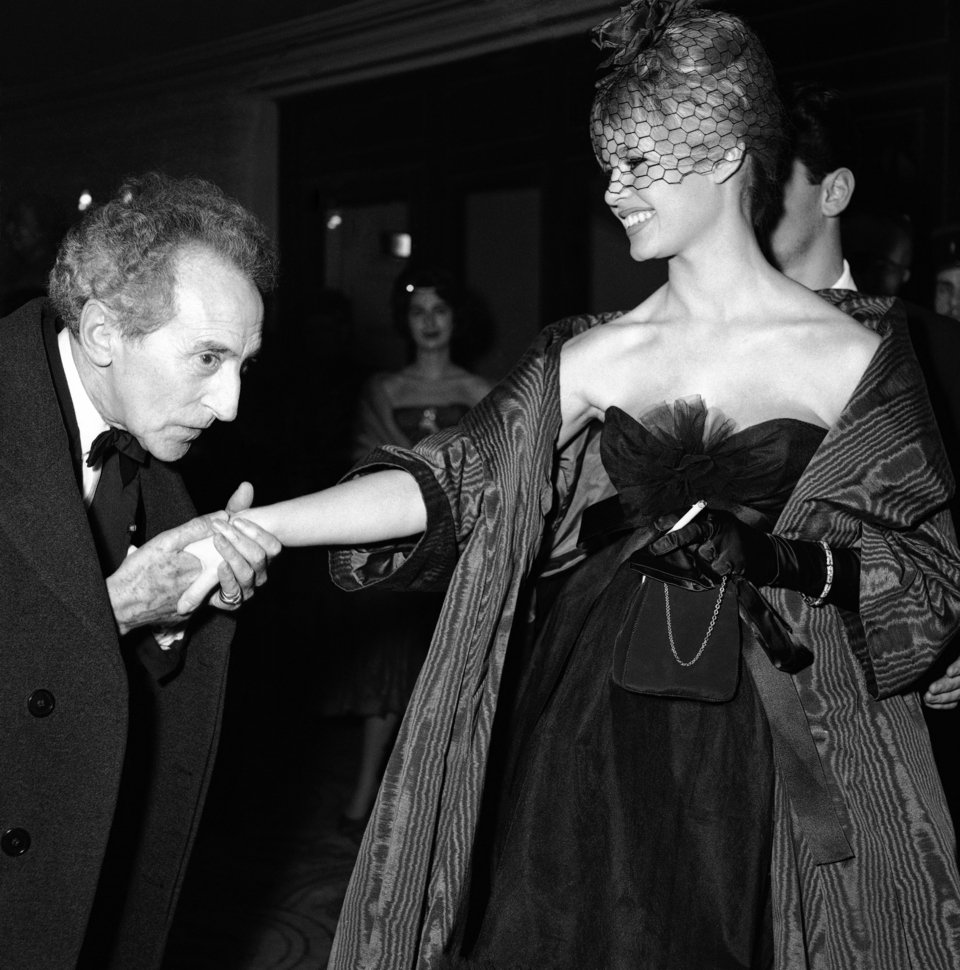 Η Μπριζίτ Μπαρντό χαμογελά, καθώς ο Γάλλος συγγραφέας, ζωγράφος και σκηνοθέτης Ζαν Κοκτό σκύβει για να φιλήσει το χέρι της, στις 22 Δεκεμβρίου 1958