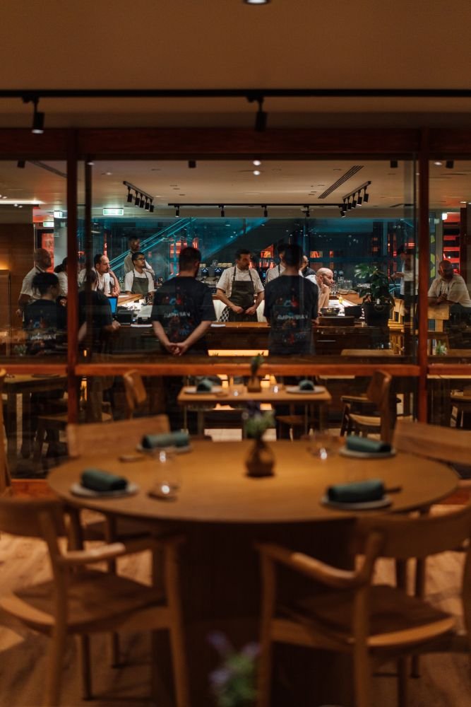 Η αισθητική του ισορροπεί ανάμεσα στο Japandi minimalism και το art-house, συνδυάζοντας γήινα και industrial υλικά, φυσικό και playful φωτισμό, καθώς και εικαστικά στοιχεία εμπνευσμένα από τον κόσμο της φύσης