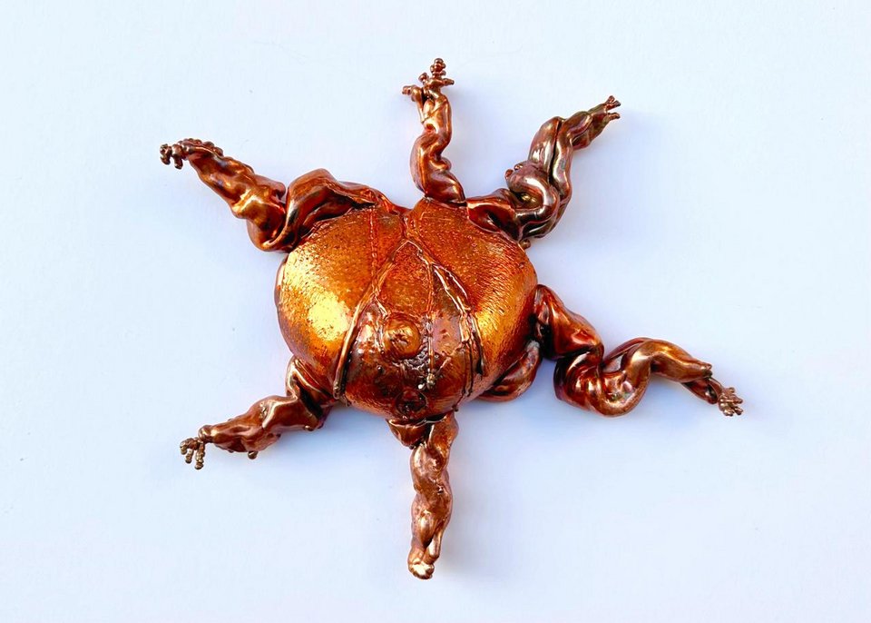 Η Μαλβίνα Παναγιωτίδη παρουσιάζει ένα υβριδικό σώμα - έντομο και ανθρώπινο μαζί, μια μεταλλική καρδιά με πολλαπλά άκρα, σαν μετάλλαξη που αιωρείται ανάμεσα στο φυλαχτό και στο τρόπαιο.