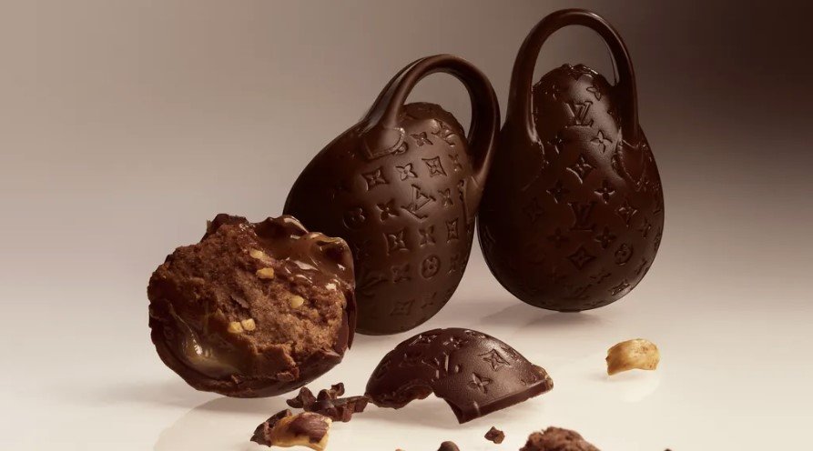 Η νέα εκδοχή επανέρχεται με πιο έντονη χρωματική ταυτότητα και ενισχυμένη έμφαση στη λεπτομέρεια, συνδυάζοντας την τεχνική ζαχαροπλαστικής με την αισθητική των αξεσουάρ πολυτελείας / LV